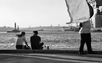 A couple sitting on a wooden pier grayscale images
